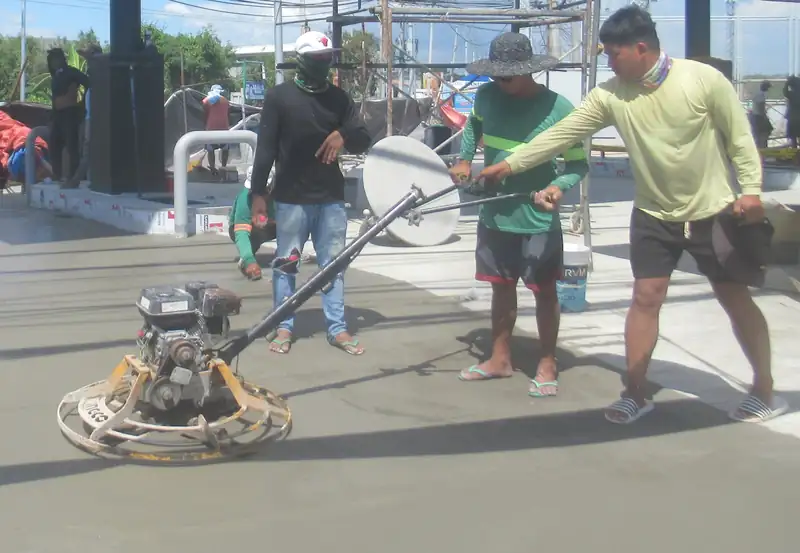 Two finishers making a second pass with power trowels