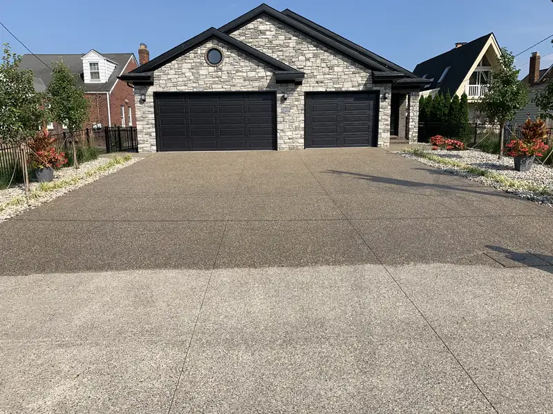 Wide exposed-aggregate driveway in front of a three-car garage