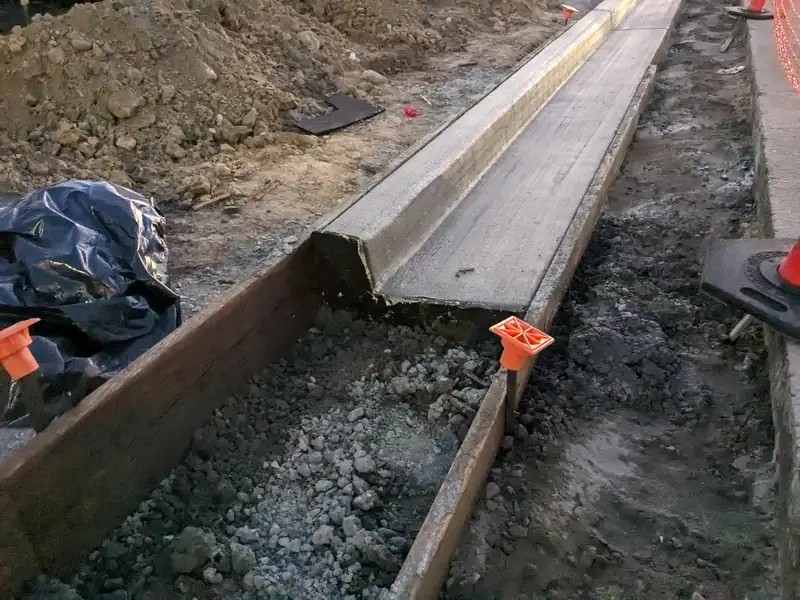 Freshly formed concrete curb and gutter beside a roadway