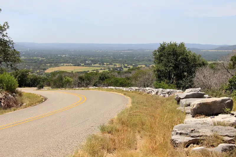 Dry-laid stone wall holding a slope above a curving drive in hilly country