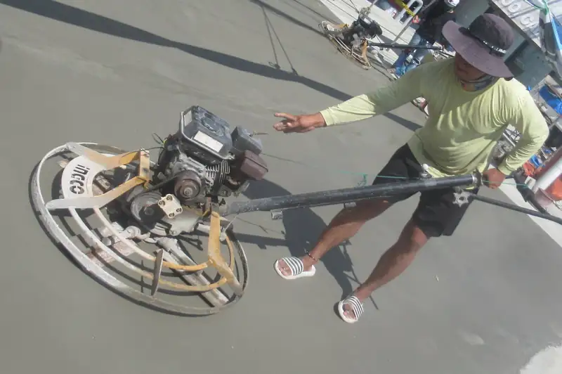 Finisher running a power trowel across a fresh concrete slab