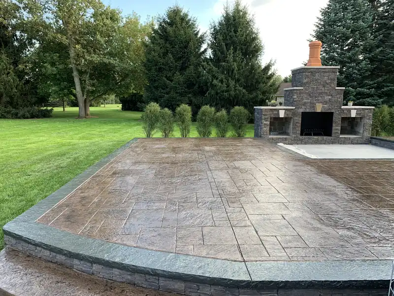 Gray stamped concrete patio with a slate-look pattern beside a lawn